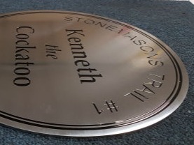 Circular stainless steel plaque with engraved and black paint filled text